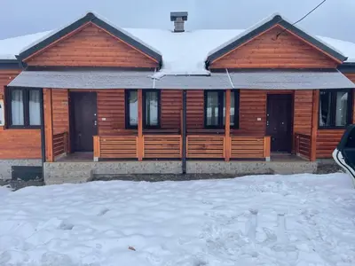 a wooden house with snow on the roof at Apartman Vuk, Crni Vrh - Stara planina in Crni Vrh