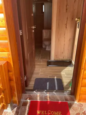 a bathroom with a toilet and a door with a welcome mat at Apartman Vuk, Crni Vrh - Stara planina in Crni Vrh