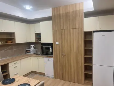 a kitchen with white cabinets and a wooden door at Apartman Dasha in Brzeće