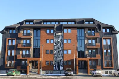 an apartment building with a sculpture in front of it at Mountain Paradise Ski In & Out - Vila Golija Kopaonik in Kopaonik