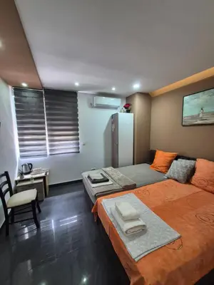 a bedroom with two beds and a table and a refrigerator at Lena lux in Jagodina