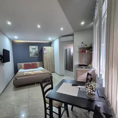a bedroom with a bed and a table and a dining room at Lena lux in Jagodina