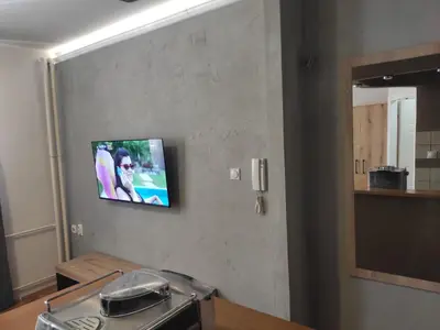 a television hanging on a wall in a kitchen at Donin apartman in Niš