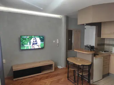 a kitchen with two stools and a tv on the wall at Donin apartman in Niš