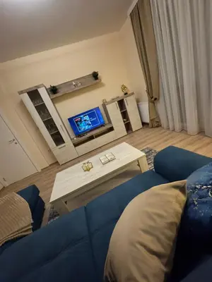 a living room with a blue couch and a tv at Jokica apartmani in Paraćin