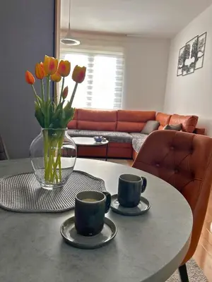 a table with two cups and a vase of flowers on it at Happiness Apartman in Vrnjci