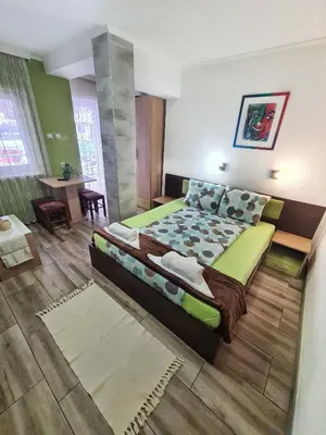 a bedroom with a large bed and a table at Vila Aleksandra 2 Studio 8 in Soko Banja