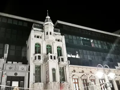 a large white building with a tower in front of a building at Fine apartments Nis in Niš