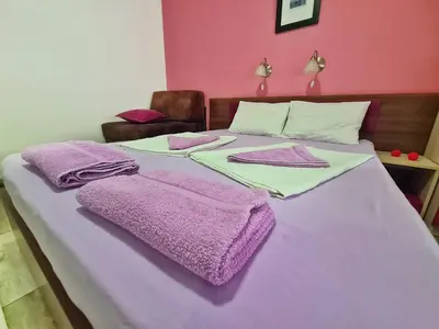 a bed with purple blankets and towels on it at Vila Aleksandra 2 Studio 11 in Soko Banja