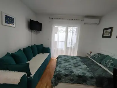 a bedroom with a bed and a couch and a window at Sofika in Vrnjačka Banja