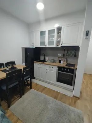a kitchen with white cabinets and a table and a stove at Sofika in Vrnjačka Banja