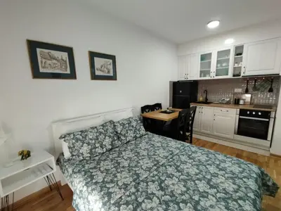 a bedroom with a bed and a desk and a kitchen at Sofika in Vrnjačka Banja