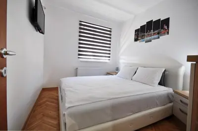 a white bedroom with a bed and a window at Apartman Cvetkovic in Vrnjačka Banja