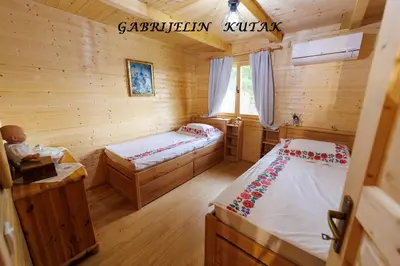 a bedroom with two beds in a log cabin at Gabrielin kutak in Mužinac