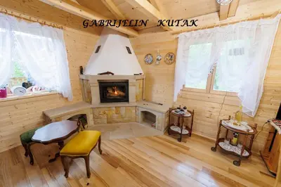 a living room with a fireplace in a log cabin at Gabrielin kutak in Mužinac