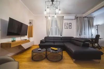 a living room with a black leather couch and a tv at Luka's apartment in Pirot