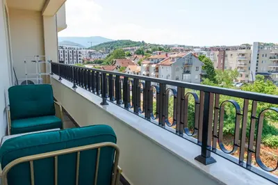 a balcony with a chair and a view of a city at In lux spa apartman 2 in Vrnjačka Banja