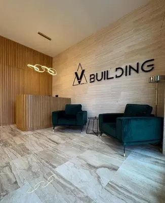 a lobby with two green couches and a building sign at In lux spa apartman 2 in Vrnjačka Banja