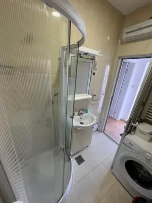 a bathroom with a shower and a sink and a washing machine at Vlasina Nature Escape in Lujinska Mala