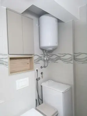 a white bathroom with a toilet and a cabinet at Janković in Vranje