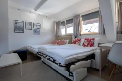 a bedroom with a bed and a desk and windows at Konaci Brvenik Suites in Kopaonik