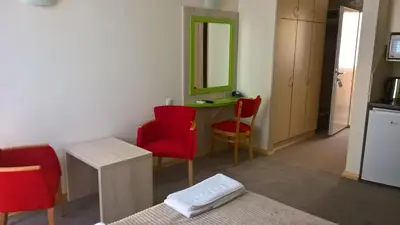 a room with red chairs and a table with a mirror at Apartments Mavesa in Vrnjačka Banja