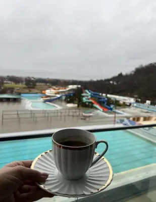 a person holding a cup of coffee next to a pool at Apartman Vića in Jagodina