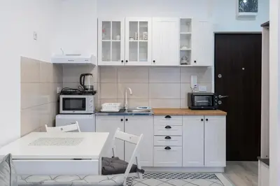 a kitchen with white cabinets and a table and a sink at Apartman Vića in Jagodina
