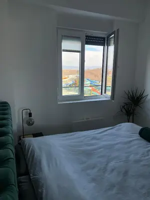 a bedroom with a white bed and two windows at Apartman Vića in Jagodina