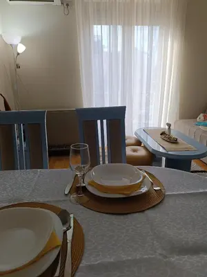 a dining room table with plates and a wine glass at Apartman Fazan in Vrnjačka Banja