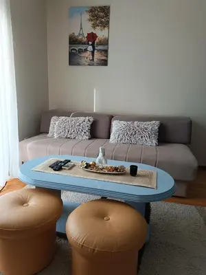 a living room with a couch and a table and two stools at Apartman Fazan in Vrnjačka Banja