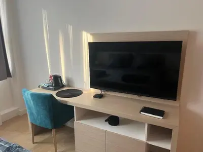 a television on a desk with a blue chair at Zepterme lux in Vrnjačka Banja