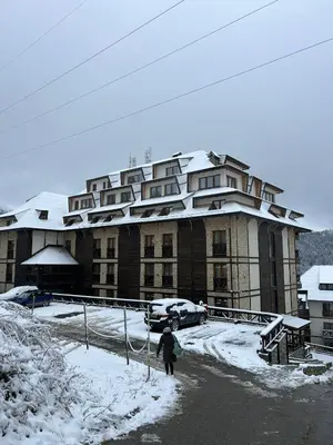 a person walking in front of a large building in the snow at Apartman Minja - Hotel Zoned Kopaonik in Kopaonik