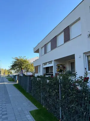 a white building with a fence next to a sidewalk at Studio 4 in Pirot