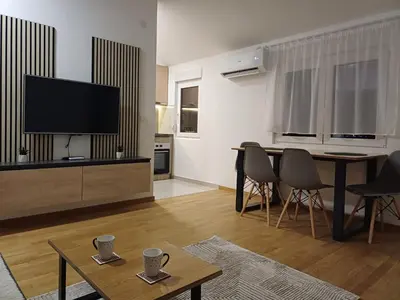 a living room with a tv and a table and chairs at Forest River Sokobanja in Soko Banja