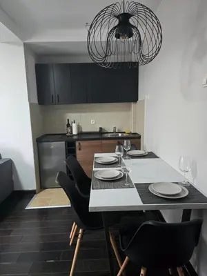 a kitchen with a table with chairs and a chandelier at Weg City Apartmani in Brzeće