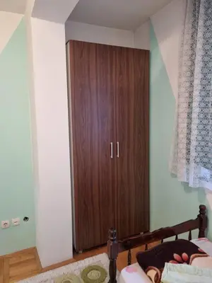 a bedroom with a wooden cabinet next to a bed at Vucko Apartmani in Prokuplje