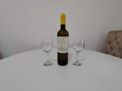 a bottle of wine and two wine glasses on a table at Apartman Peca in Vrnjci