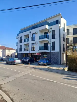 a white building with cars parked in front of it at Apartman Peca in Vrnjci