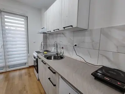 a white kitchen with a sink and a window at Apartman Peca in Vrnjci