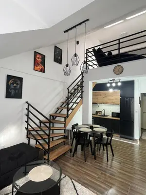 a living room with a staircase and a table and chairs at Central Duplex Apartment in Zaječar