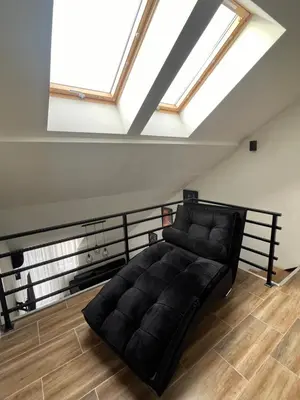 a black couch in a room with a skylight at Central Duplex Apartment in Zaječar