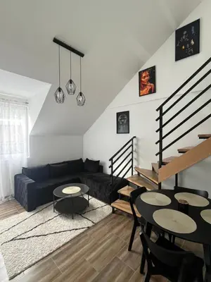 a living room with a black couch and tables at Central Duplex Apartment in Zaječar