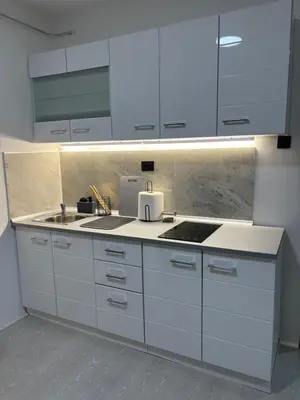 a kitchen with white cabinets and a sink at Fenix Apartman III in Zaječar