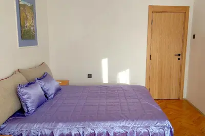 a bedroom with a purple bed and a wooden door at Apartmani HARMONIJA - Sokobanja in Soko Banja