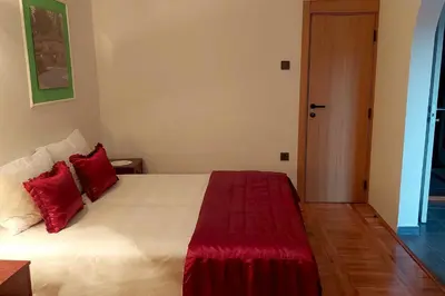 a bedroom with a large white bed with red pillows at Apartmani HARMONIJA - Sokobanja in Soko Banja
