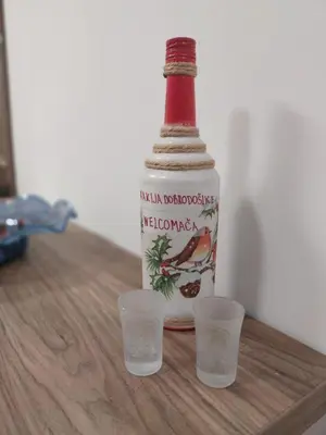 a bottle and two cups on a wooden table at Bella Winterhouse Kopaonik in Kopaonik