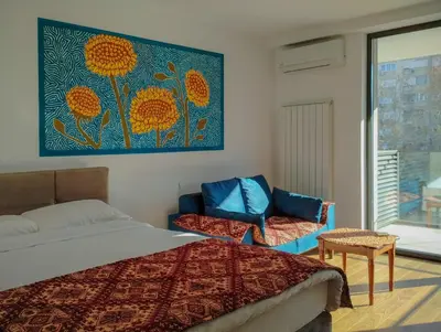 a bedroom with a bed and a chair and a painting at Planet Residence-Studio Solis in Niš