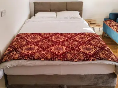 a bed with a red and white blanket on it at Planet Residence-Studio Solis in Niš