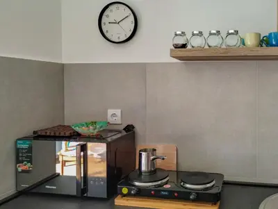 a kitchen with a microwave and a clock on the wall at Planet Residence-Studio Solis in Niš